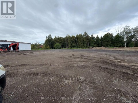 A large, empty parking lot with a building and trees in the background.
