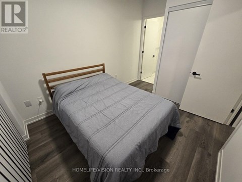 A bedroom with a bed, wooden headboard, and striped carpet.