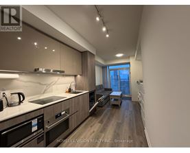 A modern kitchen with dark wood floors and stainless steel appliances.