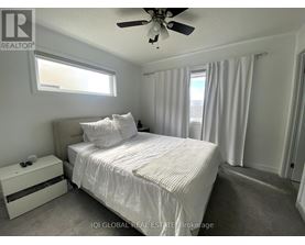 A bedroom with a bed, nightstand, and window.