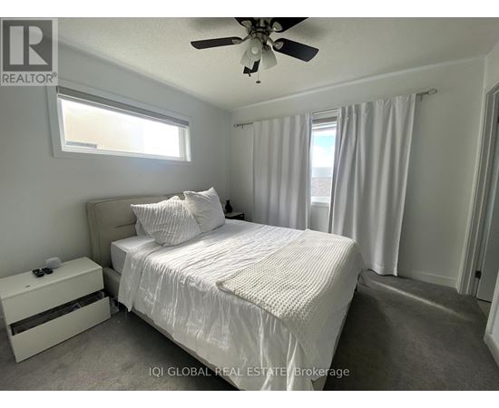 A bedroom with a bed, nightstand, and window.