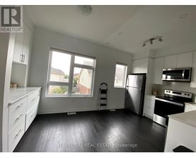 A kitchen with white cabinets and a black fridge.