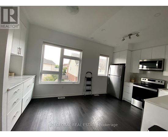 A kitchen with white cabinets and a black fridge.