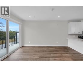 A spacious room with wooden flooring and white walls, part of a real estate listing.