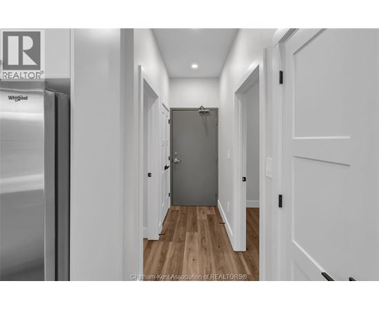 A hallway with a wooden floor and white walls.