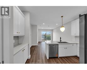 A modern kitchen with white cabinets and a wooden floor.
