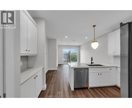 A modern kitchen with white cabinets and a wooden floor.