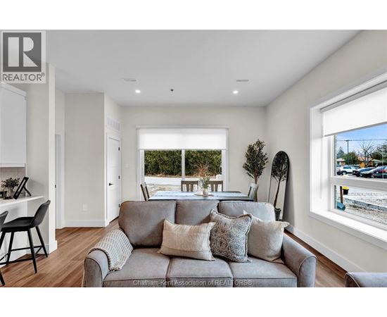 A living room with a grey couch and a window overlooking a street.