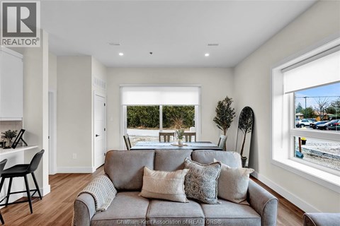 A living room with a grey couch and a window overlooking a street.
