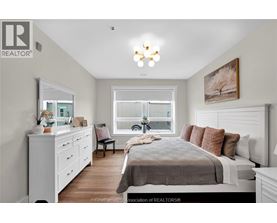 A well-lit bedroom with a large bed, a dresser, and a window.