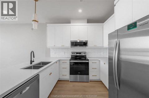A modern kitchen with white cabinets and stainless steel appliances.