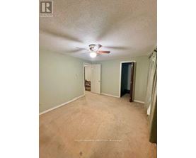 A room with a ceiling fan and a door at the end.