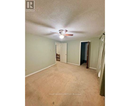 A room with a ceiling fan and a door at the end.