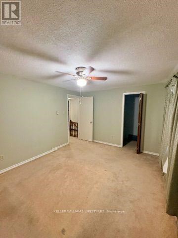 A room with a ceiling fan and a door at the end.
