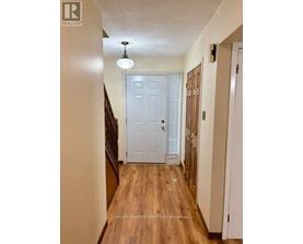 A hallway with a white door and wooden floors.