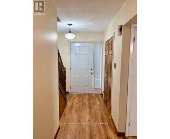 A hallway with a white door and wooden floors.