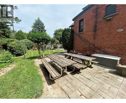 A backyard with a picnic table and a brick building.