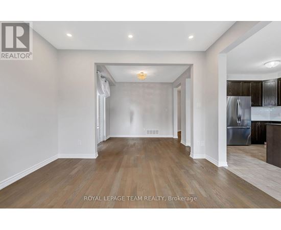 A spacious room with wooden flooring and white walls.