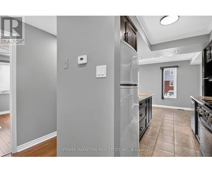 A kitchen with a refrigerator, cabinets, and a tiled floor.