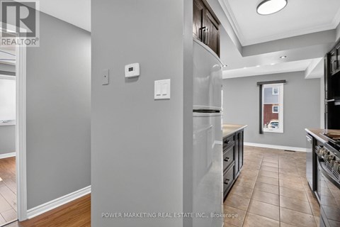 A kitchen with a refrigerator, cabinets, and a tiled floor.