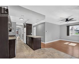 A well-lit kitchen with dark wood cabinets and a fan on the ceiling.