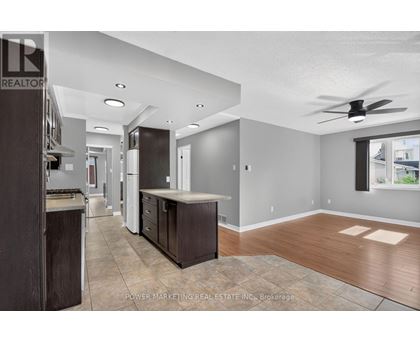 A well-lit kitchen with dark wood cabinets and a fan on the ceiling.