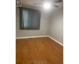 A room with wooden flooring and a window with blinds.