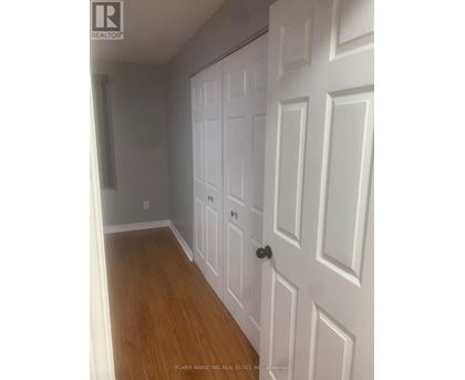 A white door with a black handle is in a room with wooden floors.