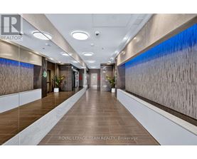 A long hallway with a plant on each side and a logo on the wall.