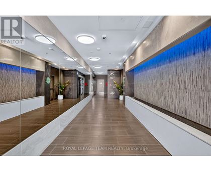 A long hallway with a plant on each side and a logo on the wall.