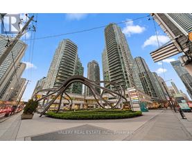 A large sculpture in the foreground of a city street with tall buildings in the background.