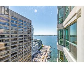 A view from a high-rise building looking down at a parking lot and a body of water.