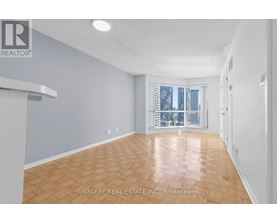 A spacious room with wooden flooring and a large window.