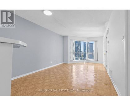A spacious room with wooden flooring and a large window.