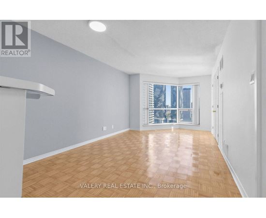 A spacious room with wooden flooring and a large window.