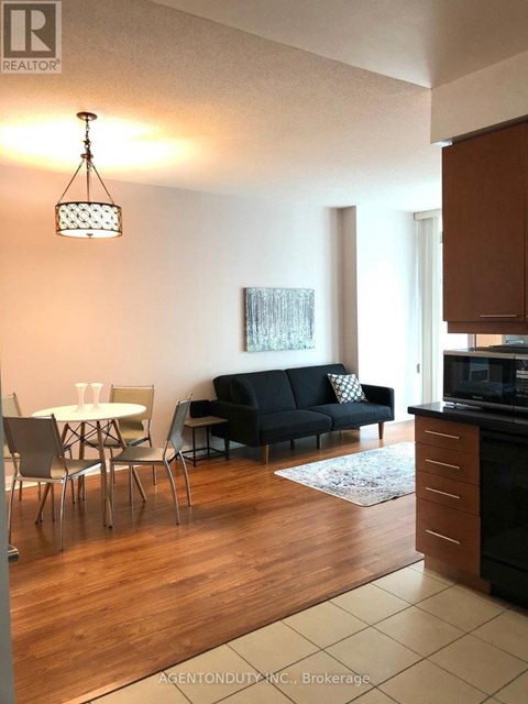 A living room with a black couch and a dining table.