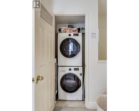 A white washer and dryer are stacked in a small space.