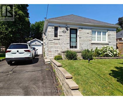 A white car is parked in front of a house with a sign that says "REALTOR".