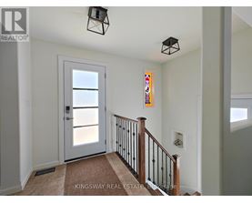 A hallway with a white door and a staircase with a black railing.