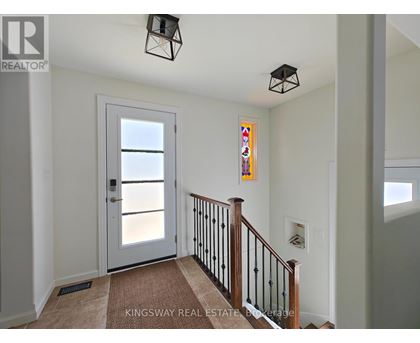 A hallway with a white door and a staircase with a black railing.