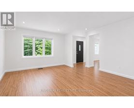 A room with wooden flooring and a large window with trees visible outside.