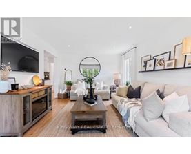 A modern living room with a white sofa, a wooden coffee table, and a TV on the wall.