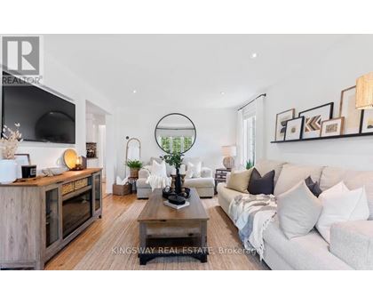A modern living room with a white sofa, a wooden coffee table, and a TV on the wall.