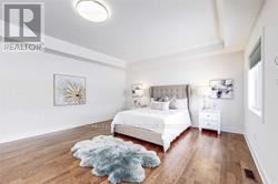 A bedroom with a white bed and a blue rug.