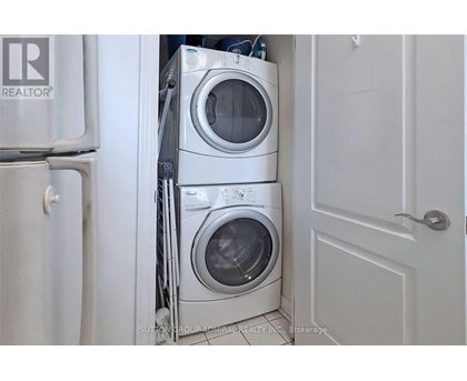 A white washing machine is stacked on top of another in a small space.