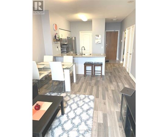 A modern kitchen with white chairs and a wooden floor.