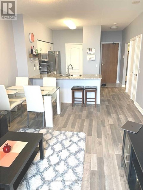A modern kitchen with white chairs and a wooden floor.