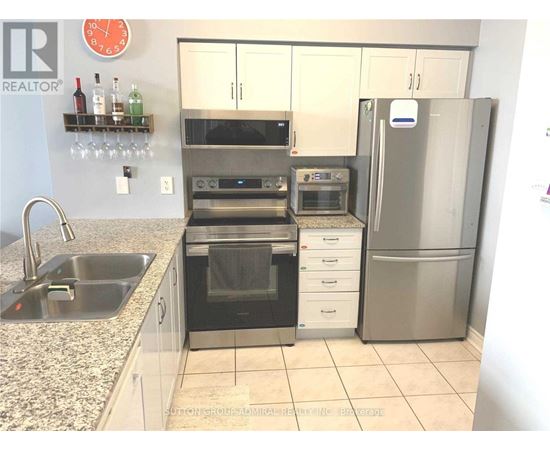 A kitchen with a refrigerator, oven, and sink.