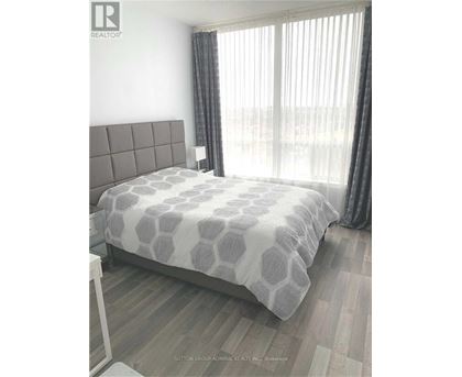 A bedroom with a large bed and a window with curtains.