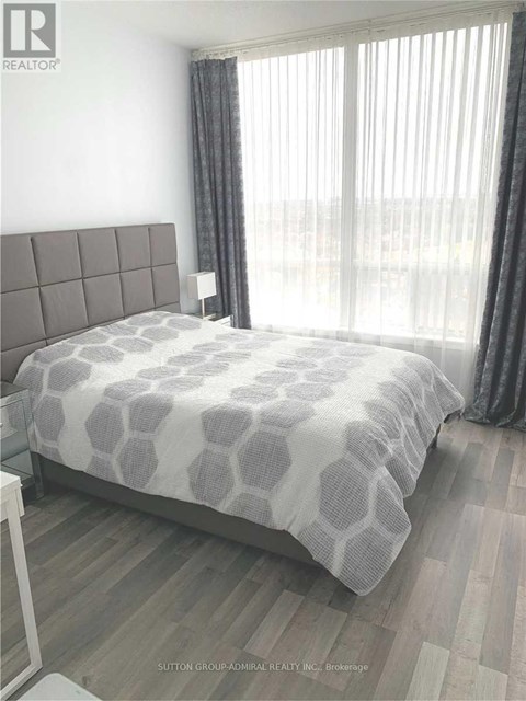 A bedroom with a large bed and a window with curtains.